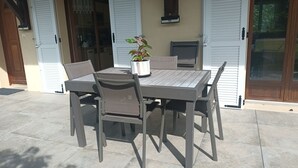 An outdoor patio with a table and four chairs, a potted plant, and a sliding glass door. - Guest rooms upstairs.  Breakfast included.  (Saillenard)