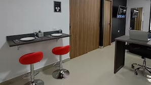 Un baño moderno con espejo, lavamanos y dos taburetes rojos.