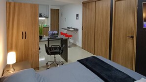 Una habitación de hotel moderna con cama, escritorio, silla y armario.
