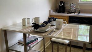 A kitchen with a white countertop, a coffee maker, a kettle, and a dishwasher.