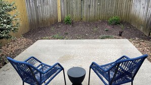A patio area with two blue chairs and a black table.