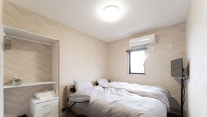 A bedroom with a bed, a bedside table, a wardrobe, and an air conditioning unit. - CS RESORT (Miyakejima)