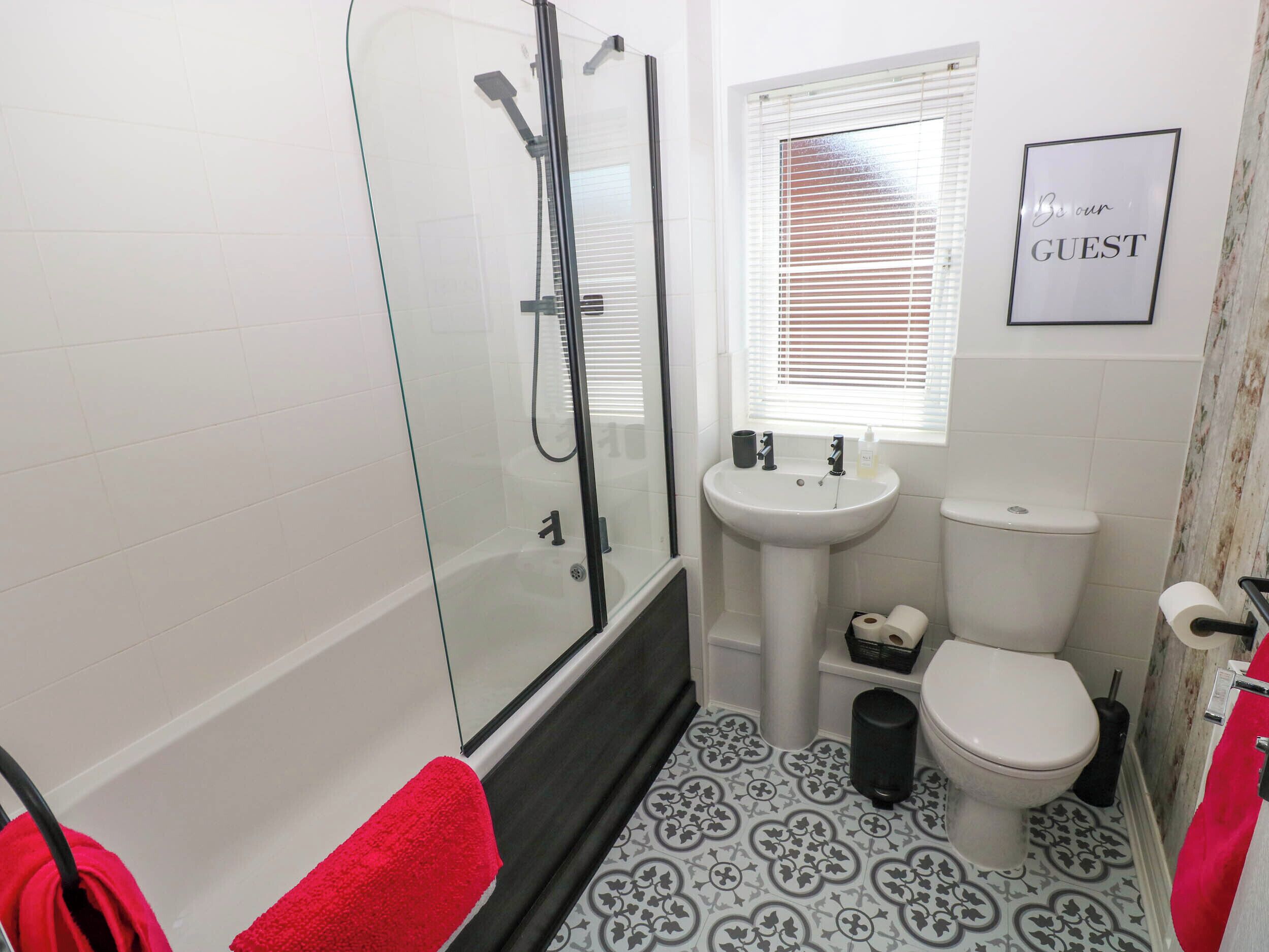 A bathroom with a glass-enclosed shower, a pedestal sink, and a toilet.