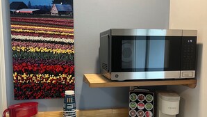 A kitchen counter with a microwave, a coffee maker, and a coffee pod holder. - Workspace near Microsoft, Meta, Lumen Field and T-Mobile Park (Bellevue)