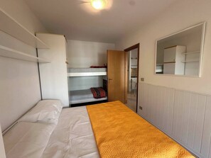 A compact room with a bunk bed, a single bed, a wardrobe, and a mirror. - Modern Flat With Shared Pool and sea Side View (San Michele al Tagliamento)