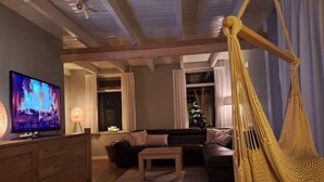 A cozy living room with a sofa, a coffee table, a TV, and a hammock.