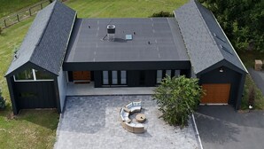 A modern house with a large patio, a garage, and a fenced yard.