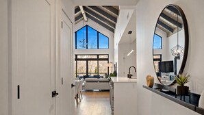 A modern interior with a central island, large windows, and a mirrored wall.