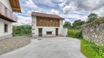 Un bâtiment moderne avec une allée en béton, des fenêtres à persiennes en bois et un mur en pierre.
