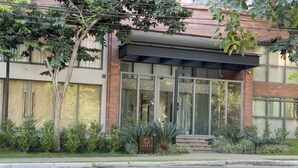A modern building with large windows, a covered entrance, and a well-maintained garden area. - Legacy Klabin (Sao Paulo)