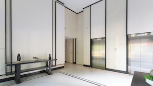 A modern lobby with a reception desk, a bench, and an elevator. - Legacy Klabin (Sao Paulo)