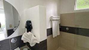 A modern bathroom with a large mirror, a sink, a towel rack, and a shower area.