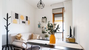 A modern living room with a sofa, chairs, a dining table, and a coffee table. There are wall art pieces and a vase with plants. - Casa Levante by Wonderful Italy (Bari)