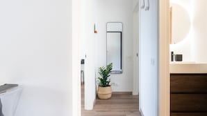 A hallway with a wooden floor, a potted plant, a mirror, and a staircase. - Casa Levante by Wonderful Italy (Bari)