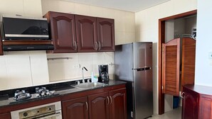 A kitchen with dark wooden cabinets, a stainless steel refrigerator, a microwave, and a stove. - Apartamento 8 personas 2 habitaciones  (Cartagena)