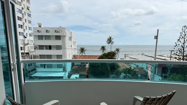 A balcony with two wicker chairs, a glass railing, and a view of the beach and buildings. - Apartamento 8 personas 2 habitaciones  (Cartagena)