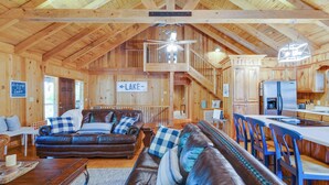 Une vaste cabane en rondins dotée d’une chambre à coucher en mezzanine, d’un salon confortable avec des canapés en cuir et d’une cuisine moderne.