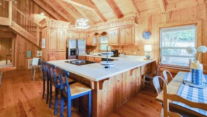 Une cabane en bois dotée d’un grand îlot de cuisine, d’une table à manger en bois et de chaises.