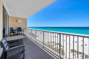 A balcony with a view of the beach, a table, chairs, and a railing. - Majestic Beach Towers 1-503 (Panama City Beach)