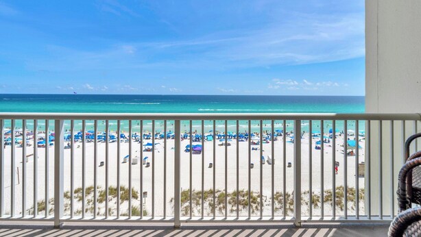 A balcony with a view of a beach with umbrellas and people. - Majestic Beach Towers 1-503 (Panama City Beach)