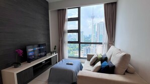 A modern living room with a large window, a flat-screen TV, a sofa, and a coffee table.