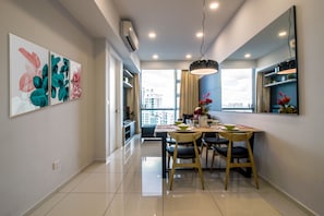 A modern dining area with a table, chairs, and a pendant light. There are wall-mounted air conditioning units and a large window with a view of buildings.