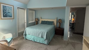 A bedroom with a skylight, a bed with a blue bedspread, a chair, and a dresser. - Cute 2br Condo. Short walk to the beach. Close to shopping, restaurants & golf. (Myrtle Beach)