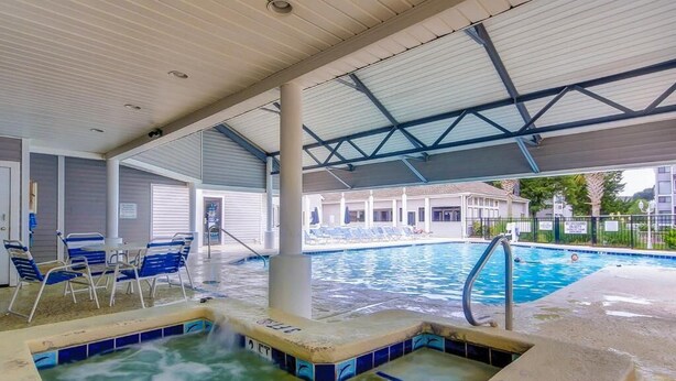 A swimming pool area with a hot tub, lounge chairs, and a covered seating area. - Cute 2br Condo. Short walk to the beach. Close to shopping, restaurants & golf. (Myrtle Beach)