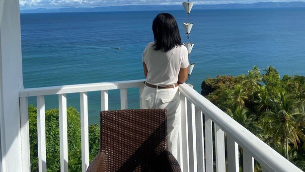 Un balcon avec vue sur l’océan et les palmiers.