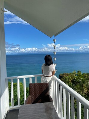 Ein Balkon mit Blick auf den Ozean und Palmen.