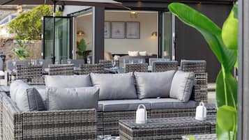 A modern outdoor seating area with wicker furniture and a glass door leading to an interior space.