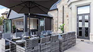 An outdoor dining area with wicker furniture and a large umbrella. - No.36 South Beach - Donnini Apartments  (Troon)