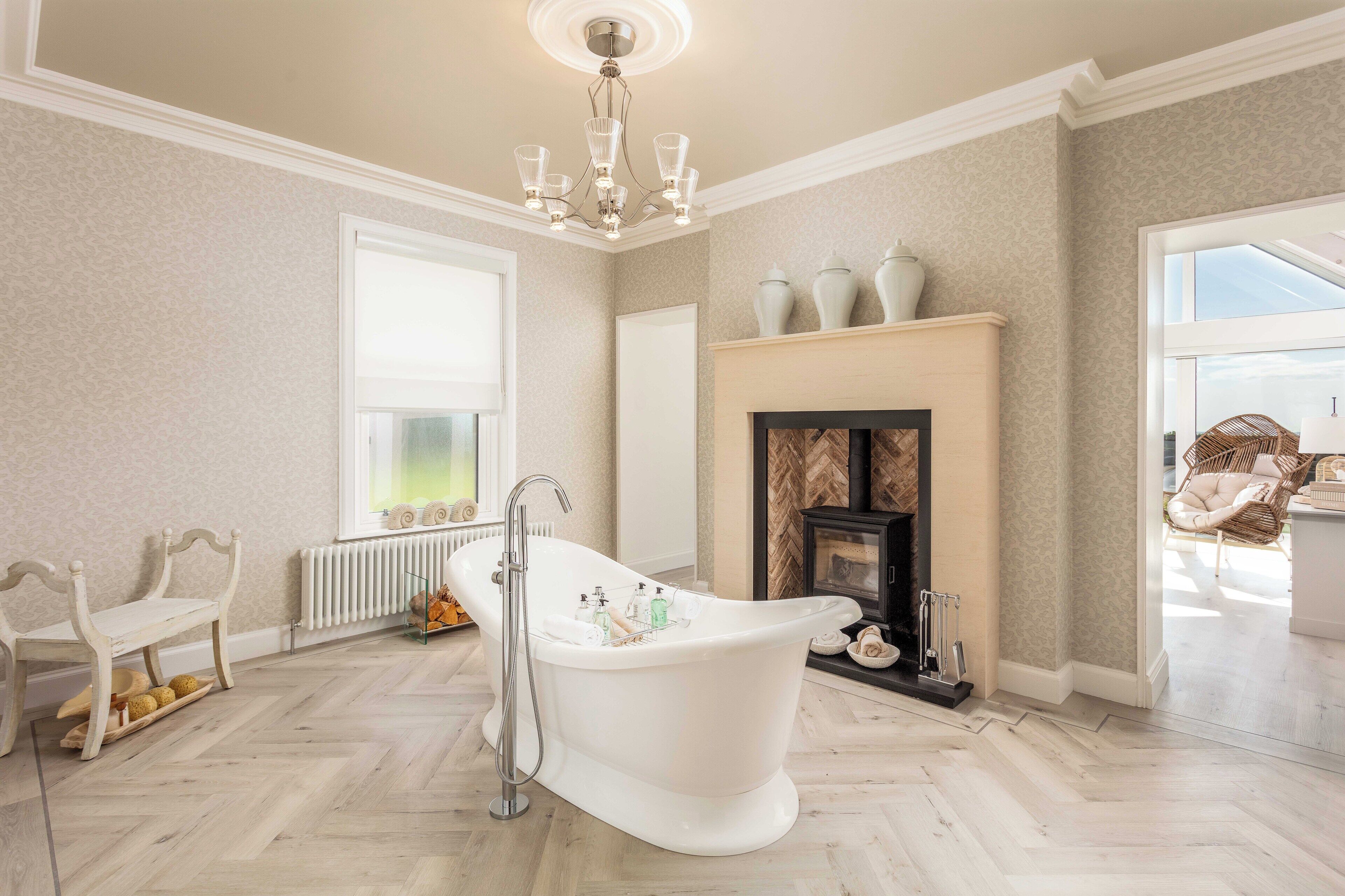 A spacious bathroom with a freestanding bathtub, a fireplace, and a large window providing natural light.