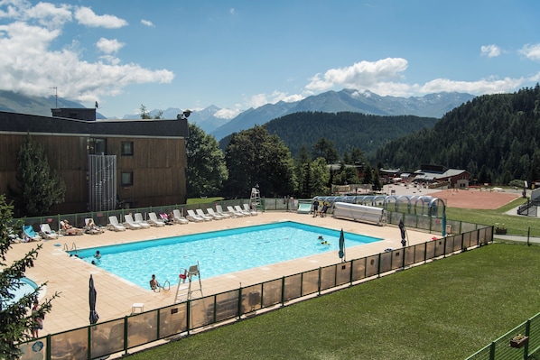 Piscina con sillas de descanso y vistas a las montañas.