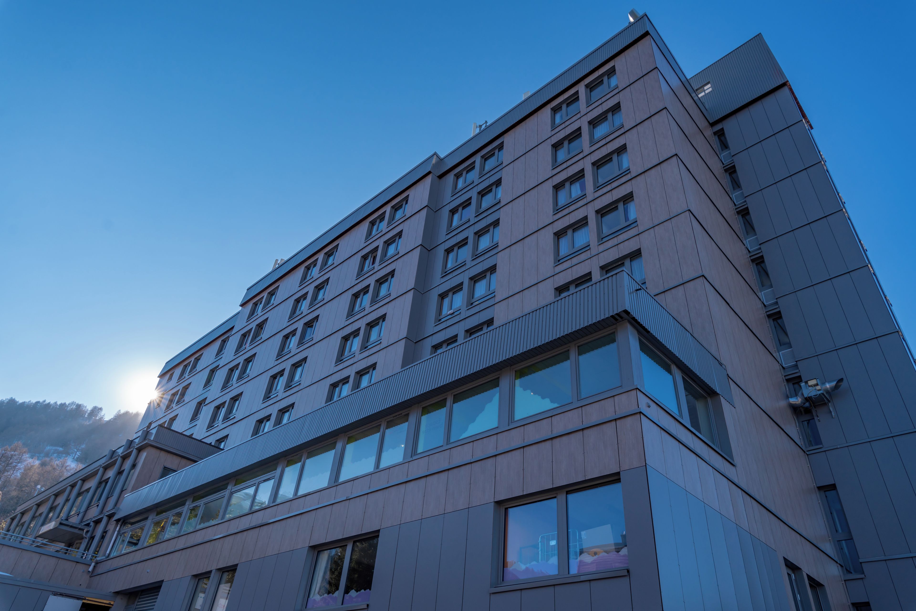 Un hôtel à plusieurs étages doté d’une architecture moderne, caractérisé par de grandes fenêtres et une entrée d’angle bien visible.