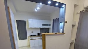A modern kitchen with white cabinets, a wooden countertop, and recessed ceiling lights.