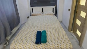 A bedroom with a bed, a headboard, a painting, and a door.