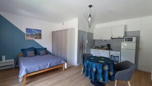 Ein Schlafzimmer mit einem Bett, einem Esstisch mit Stühlen, einer Küchenzeile und einem Badezimmer mit Duschvorhang.