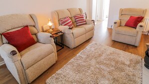 Una sala de estar con dos sillones reclinables, una mesita con una lámpara y una alfombra mullida.