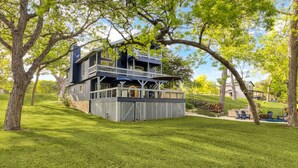A two-story house with a balcony and a deck, surrounded by trees and a well-maintained lawn.