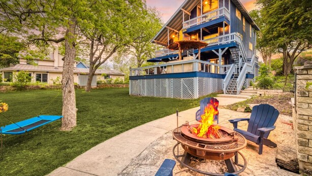A two-story house with a deck, a fire pit, and outdoor seating.