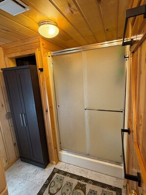 A wooden interior with a sliding glass door, a dark cabinet, and a patterned rug.