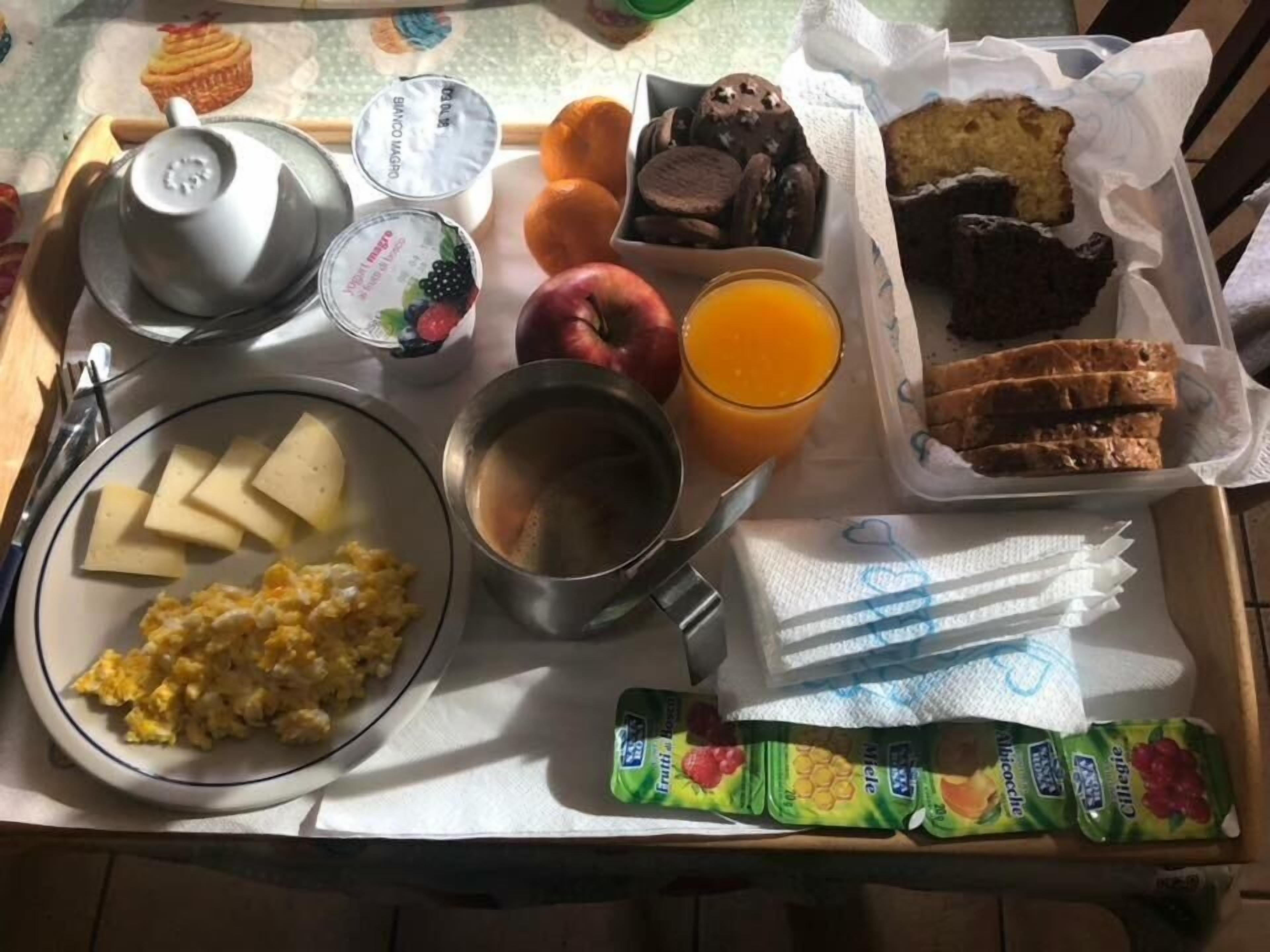 A breakfast tray with various food items including eggs, toast, fruit, and juice.