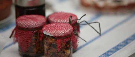 Three small jars with red lids and mesh covers on a table.