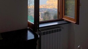 A room with a large window offering a view of a cityscape and mountains. - L' ARANCIO IN FIORE (Sant'Agnello)