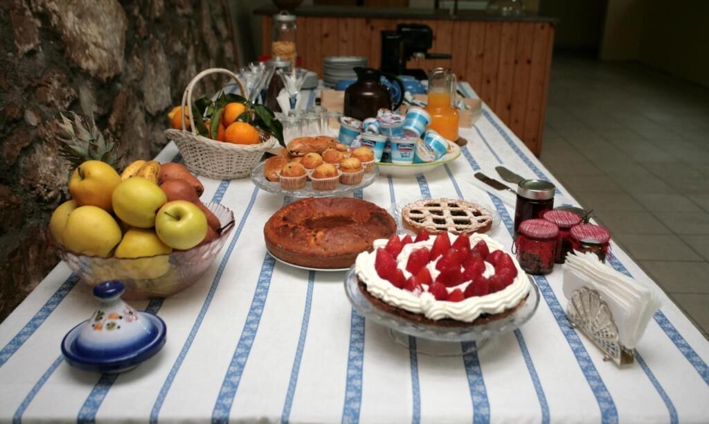 Un buffet de petit-déjeuner proposant une variété de fruits, de viennoiseries et de boissons, le tout disposé sur une nappe à rayures.