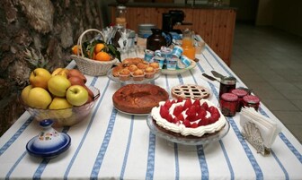 Un bufé de desayuno con diversas frutas, bollería y bebidas sobre un mantel a rayas.