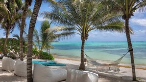 A beach with white sand, palm trees, and a hammock. - The Residence: Private 3BR Beachfront Villa (Tulum)