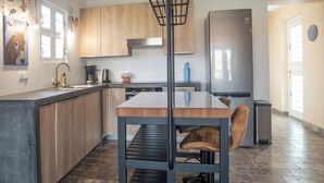 Una cuina moderna amb armaris de fusta, un frigorífic d'acer inoxidable, una cafetera i una taula de dinar amb cadires.