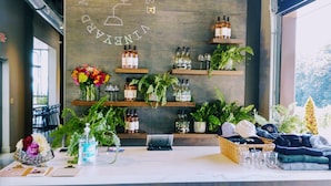 A reception area with a wooden wall displaying the name 'REVERED TERRA VINE'. There are shelves with wine bottles, a laptop, and a basket with hats and glasses.